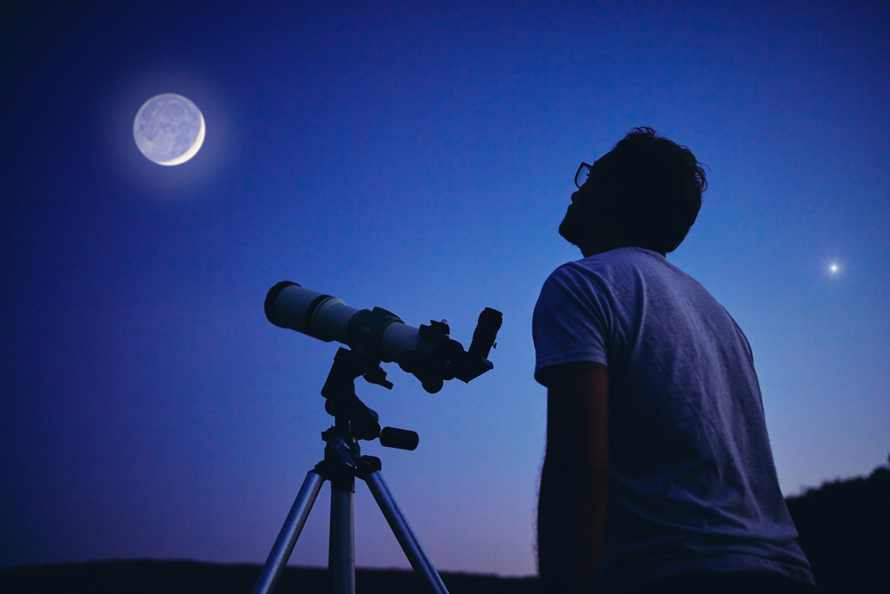 A person with a telescope watching at the stars